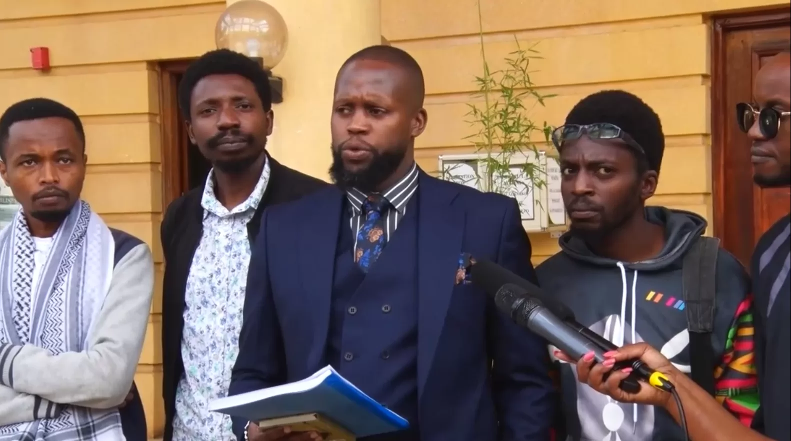 Photo of Nicholas Wambugu, Chris Wamae, Brian Adagala and Markdenver Kariuki with their Lawyer; Ian Mutiso (C) outside Milimani Law Courts